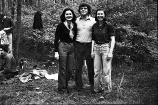Three young people standing together in a wooded area, black and white photograph from the 1970s